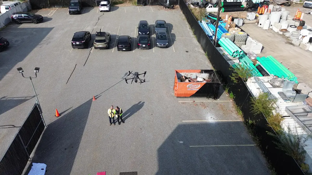 Vue aérienne zénithale d'une équipe de pilotes de drone en gilets de sécurité sur un site commercial de Gatineau