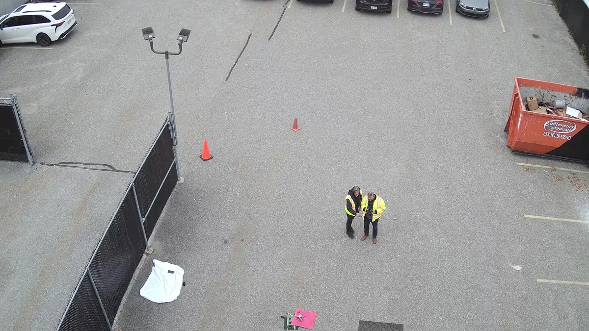 Deux pilotes de drone en gilets de sécurité sur un site de Gatineau, vus du ciel